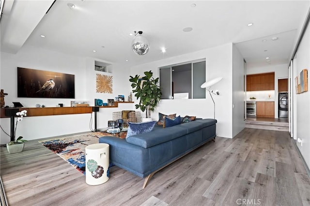 living room with light wood-type flooring, washer / dryer, beverage cooler, and recessed lighting