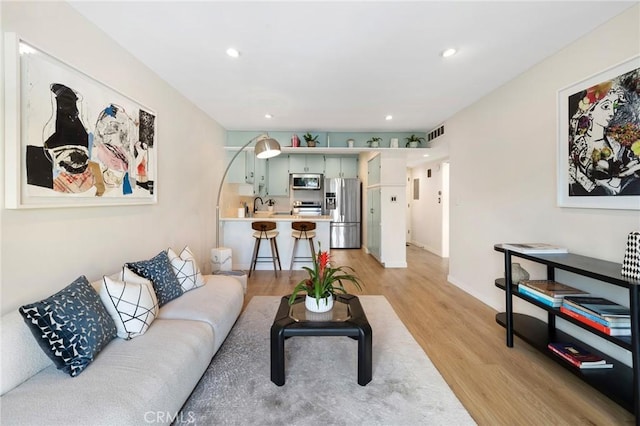 living room with light wood-type flooring, visible vents, and recessed lighting