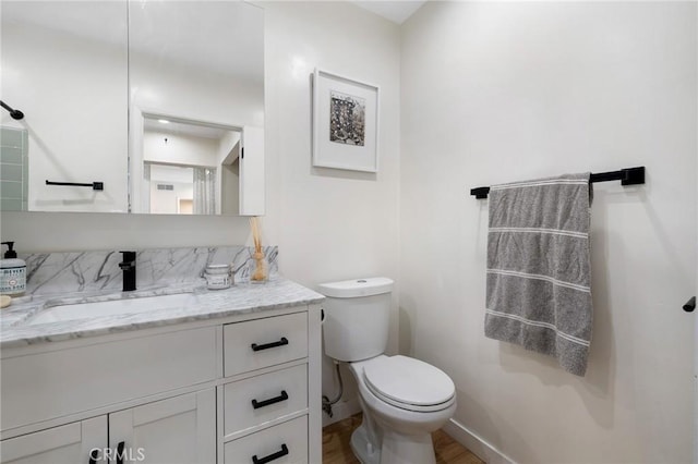 bathroom with toilet, baseboards, wood finished floors, and vanity