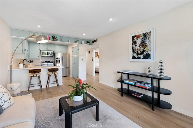 living room featuring baseboards, recessed lighting, visible vents, and light wood-style floors