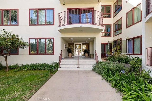 entrance to property with a balcony and stucco siding