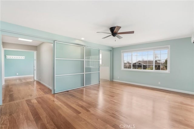 unfurnished bedroom featuring a closet, a ceiling fan, baseboards, and wood finished floors