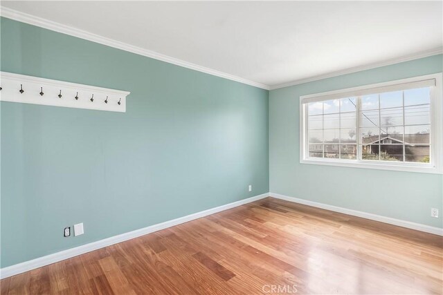 unfurnished room with ornamental molding, baseboards, and wood finished floors