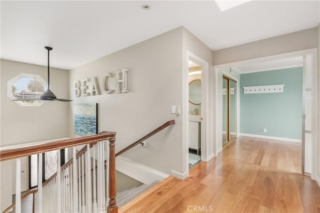 hallway featuring an upstairs landing, light wood finished floors, and baseboards