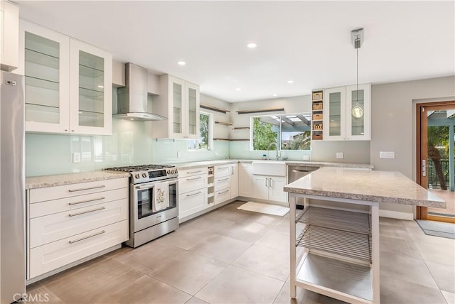 kitchen featuring light stone countertops, open shelves, a sink, stainless steel appliances, and wall chimney range hood