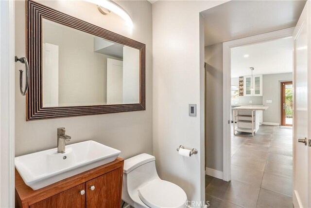 half bathroom featuring vanity, toilet, and baseboards