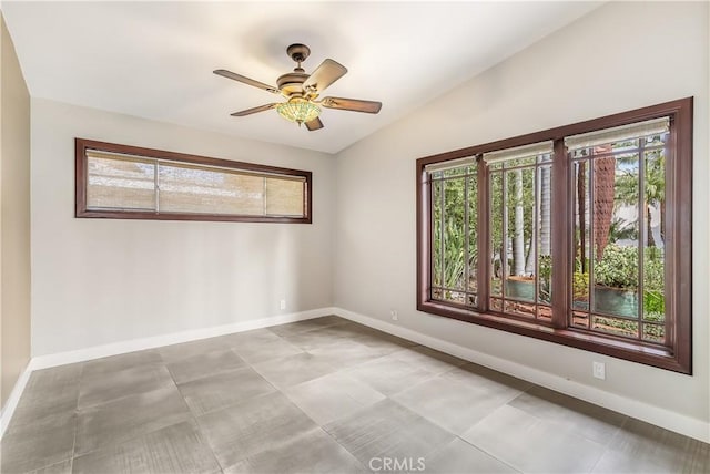 empty room featuring a wealth of natural light, baseboards, and lofted ceiling