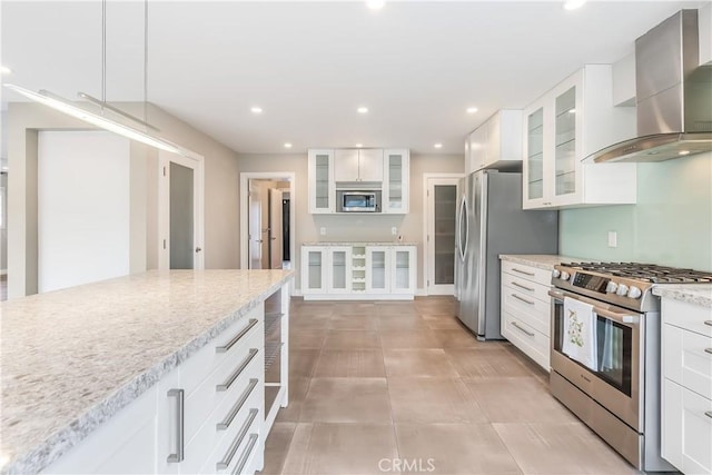 kitchen featuring light stone counters, white cabinetry, recessed lighting, appliances with stainless steel finishes, and wall chimney range hood