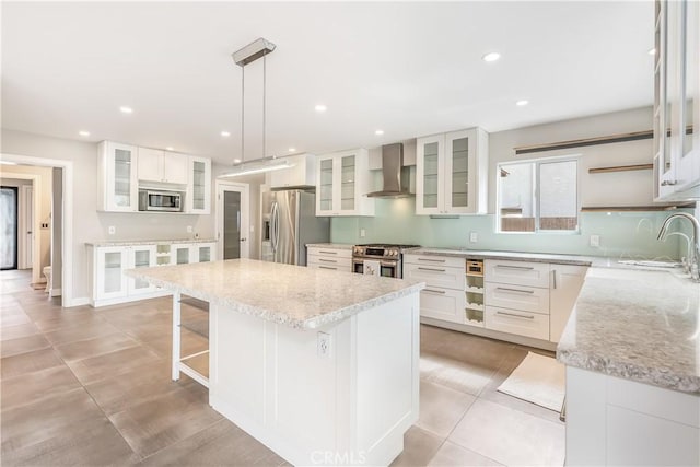 kitchen with a breakfast bar, a kitchen island, recessed lighting, stainless steel appliances, and wall chimney exhaust hood