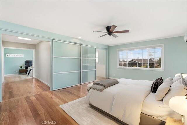 bedroom with ceiling fan, a closet, baseboards, and wood finished floors