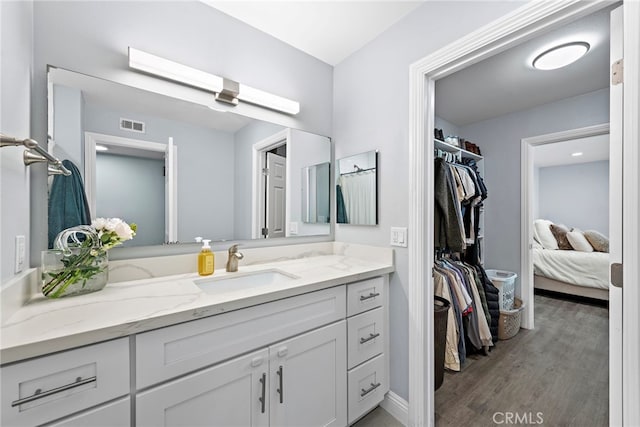 bathroom featuring connected bathroom, a skylight, wood finished floors, vanity, and visible vents