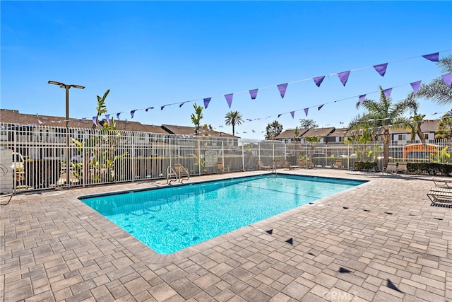 pool with a patio, fence, and a residential view