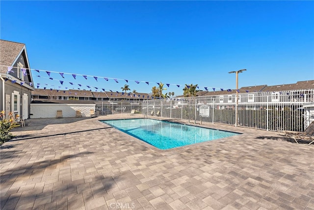 community pool featuring a residential view, a patio area, and fence