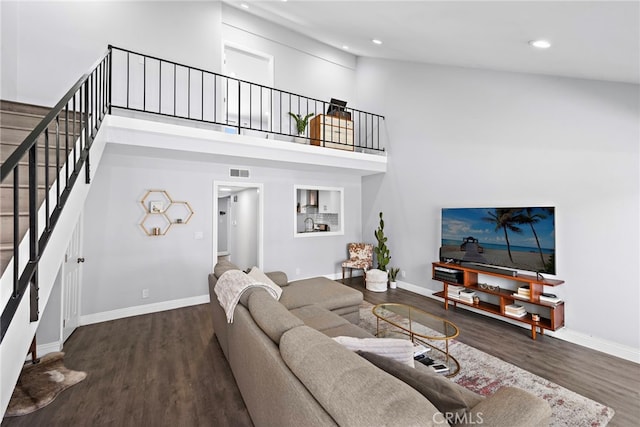 living area featuring a towering ceiling, baseboards, visible vents, and dark wood-type flooring