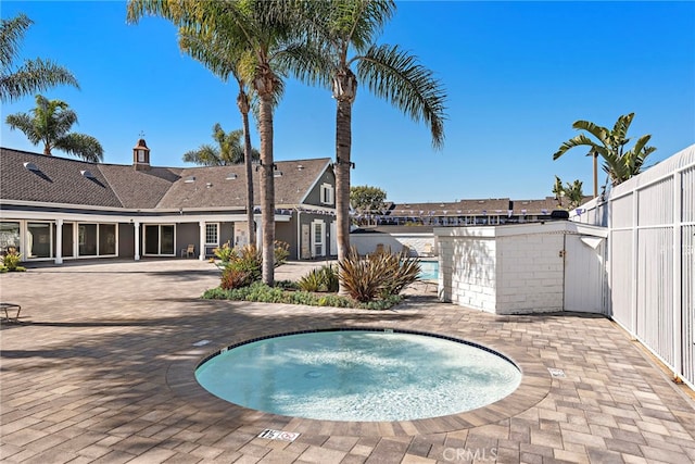 view of pool with a patio area, fence, and a hot tub