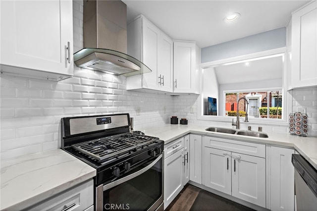 kitchen featuring white cabinetry, wall chimney exhaust hood, appliances with stainless steel finishes, and a sink