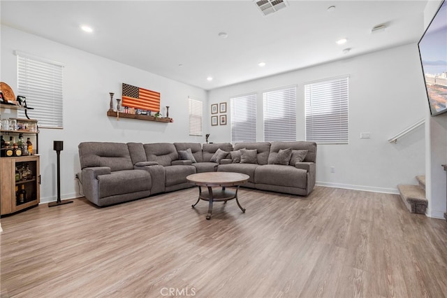 living room with light wood-type flooring, visible vents, a healthy amount of sunlight, and stairway