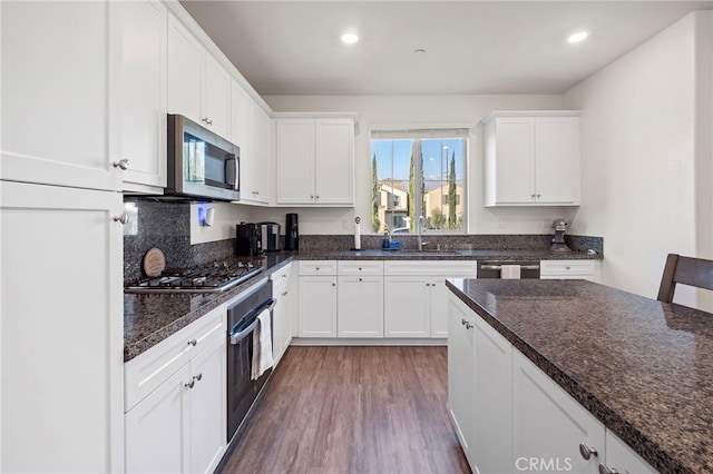 kitchen with white cabinetry, stainless steel appliances, a sink, and wood finished floors