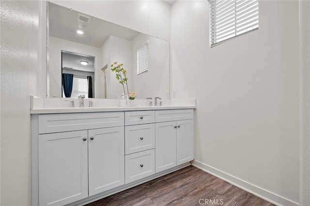 bathroom with a sink, double vanity, visible vents, and wood finished floors