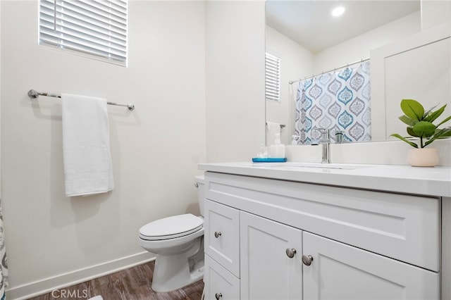 bathroom featuring toilet, wood finished floors, a shower with shower curtain, baseboards, and vanity