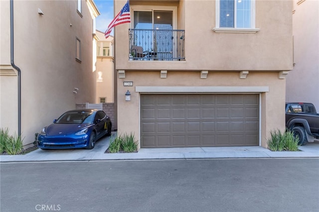 exterior space featuring concrete driveway, a garage, stucco siding, and a balcony