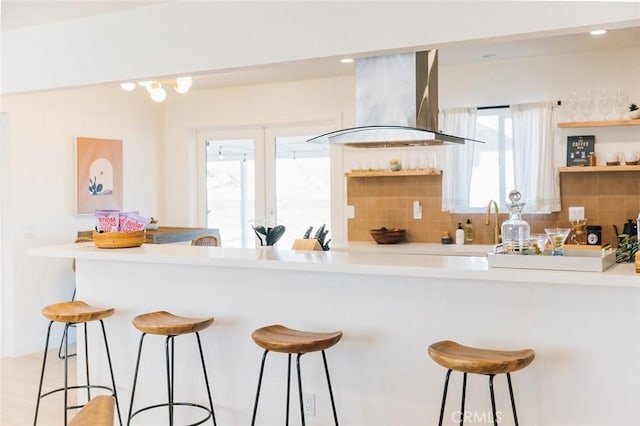 4883 Avenida La Candela, Joshua Tree, CA 92252 - kitchen with island range hood, open shelves, a kitchen bar, decorative backsplash, and light countertops
