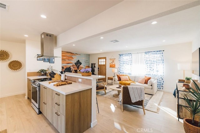 4883 Avenida La Candela, Joshua Tree, CA 92252 - kitchen with island range hood, stainless steel stove, modern cabinets, light wood-type flooring, and light countertops