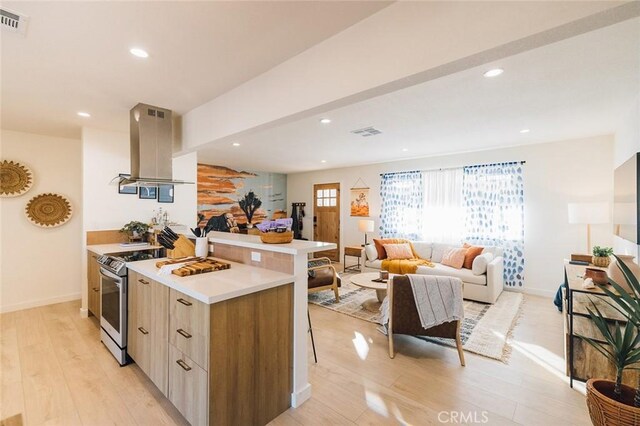 4883 Avenida La Candela, Joshua Tree, CA 92252 - kitchen with island range hood, stainless steel stove, modern cabinets, light wood-type flooring, and light countertops