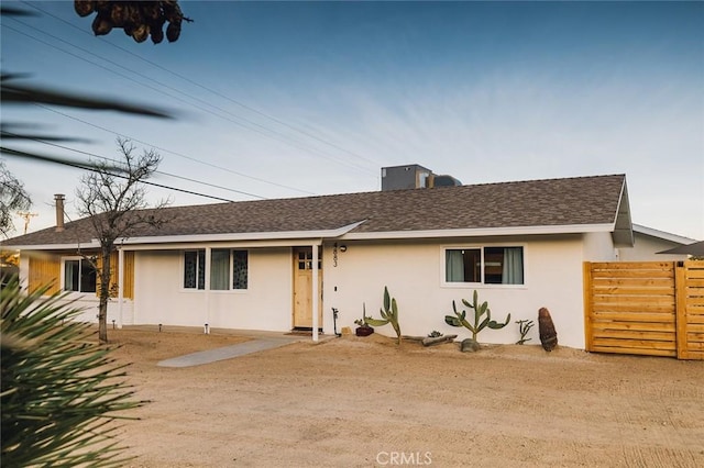 view of front of home with a shingled roof, fence, and stucco siding