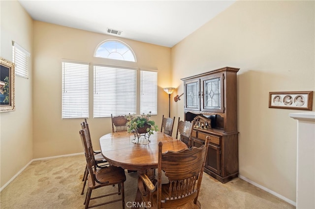 dining space with baseboards, visible vents, and light colored carpet