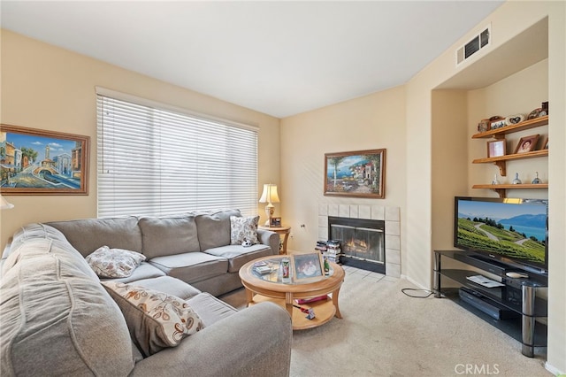 living room with a fireplace, visible vents, and light colored carpet