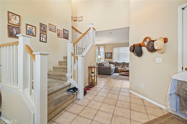 staircase featuring baseboards, a towering ceiling, and tile patterned floors