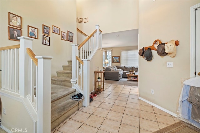 stairs with tile patterned flooring, baseboards, and a high ceiling