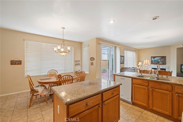 kitchen with dishwasher, a kitchen island, brown cabinets, pendant lighting, and a sink