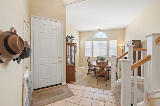 entryway featuring stairs, light tile patterned floors, light carpet, and visible vents