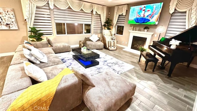 living area with baseboards, wood finished floors, and a glass covered fireplace