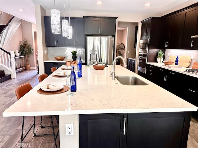 kitchen with stainless steel appliances, a breakfast bar, a sink, and a kitchen island with sink