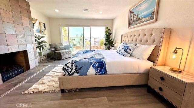 bedroom featuring visible vents, wood finished floors, access to outside, a fireplace, and recessed lighting