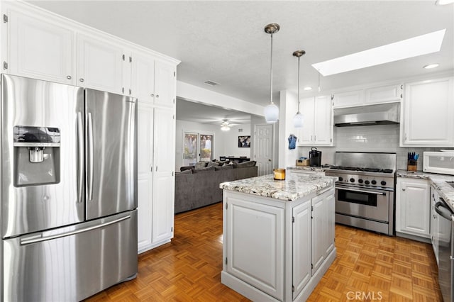 kitchen featuring under cabinet range hood, a kitchen island, white cabinetry, appliances with stainless steel finishes, and a skylight