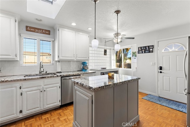 kitchen featuring a sink, backsplash, a textured ceiling, a center island, and dishwasher