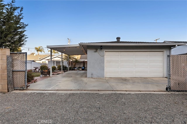 garage with a gate, a carport, and fence