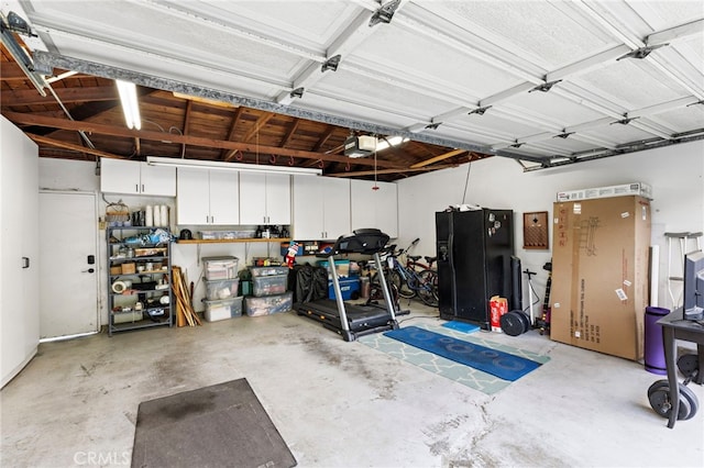 garage featuring black fridge with ice dispenser and a garage door opener