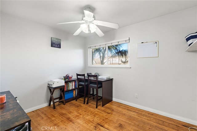 home office with a ceiling fan, baseboards, and wood finished floors