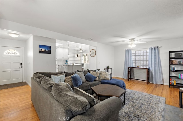 living area featuring visible vents, baseboards, light wood-style flooring, and a ceiling fan