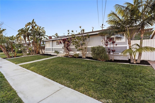 view of front of home featuring fence, stucco siding, and a front yard