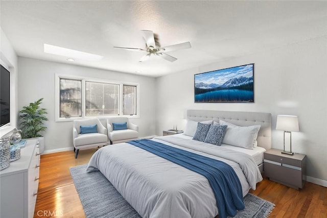 bedroom with light wood finished floors, baseboards, and ceiling fan