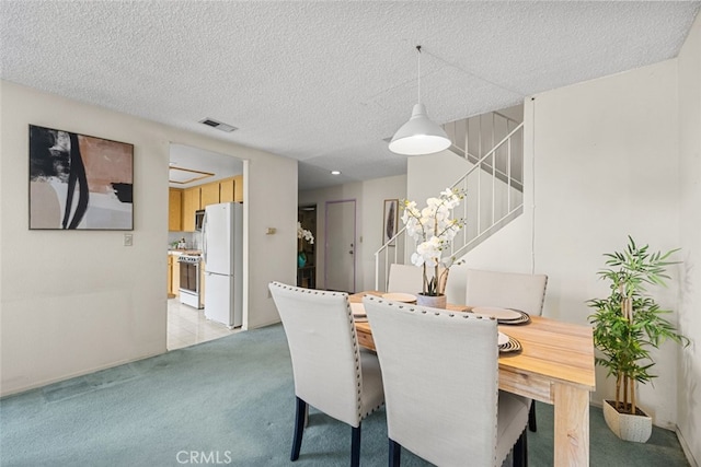 dining space with light carpet, visible vents, a textured ceiling, and stairs