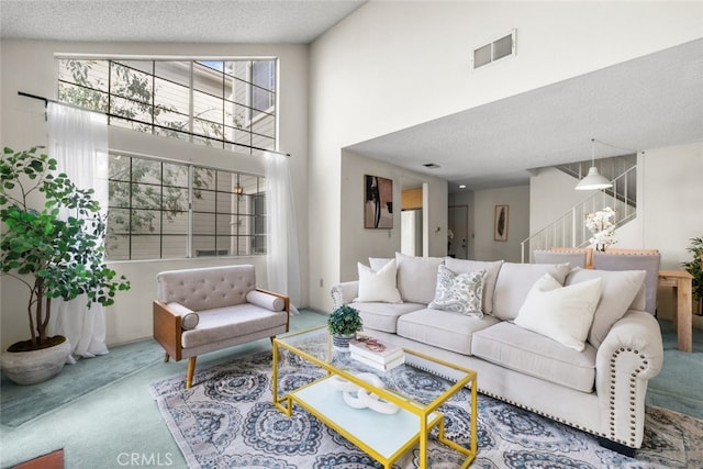 carpeted living room featuring a textured ceiling, stairway, a towering ceiling, and visible vents