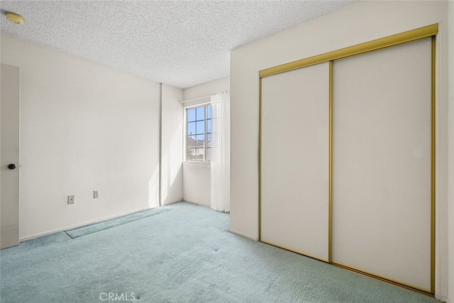 unfurnished bedroom featuring light carpet, a closet, and a textured ceiling