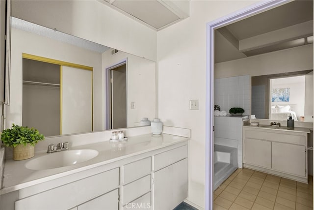 full bath featuring a washtub, vanity, and tile patterned floors